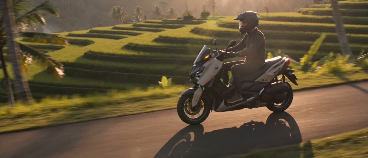 Rider on a maxi-scooter between Bali rice terraces at golden hour